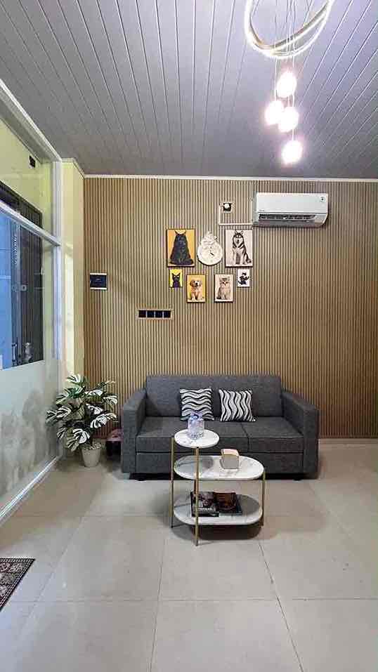 Ruang tamu nyaman dengan sofa abu-abu, meja kopi, dan dekorasi dinding bertema kucing.